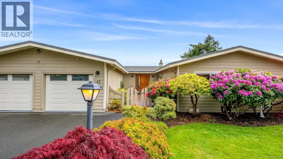 Stunning details including exterior lighting, gated entry, and mature flowering plants.