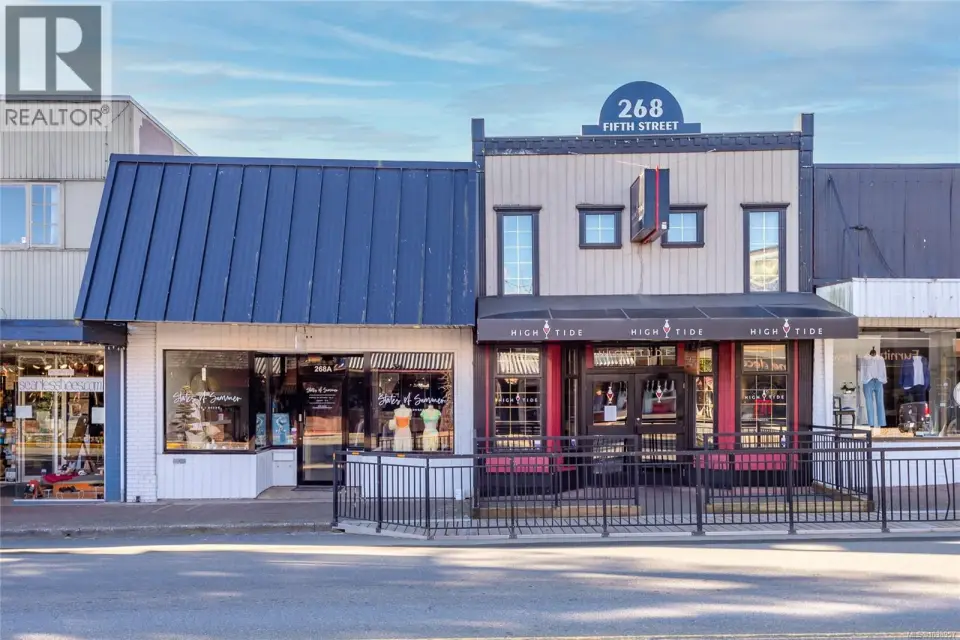 Commercial building featuring two distinct storefronts, a dark blue metal roof, and a prominent address sign