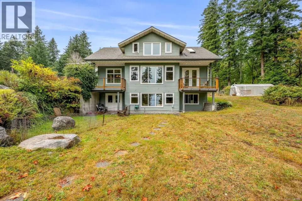 Multi-level exterior with extensive window placements, two upper-level balconies, and a ground-level patio
