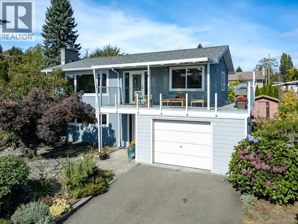 Two-story exterior with a covered upper deck, an attached garage, and a paved driveway