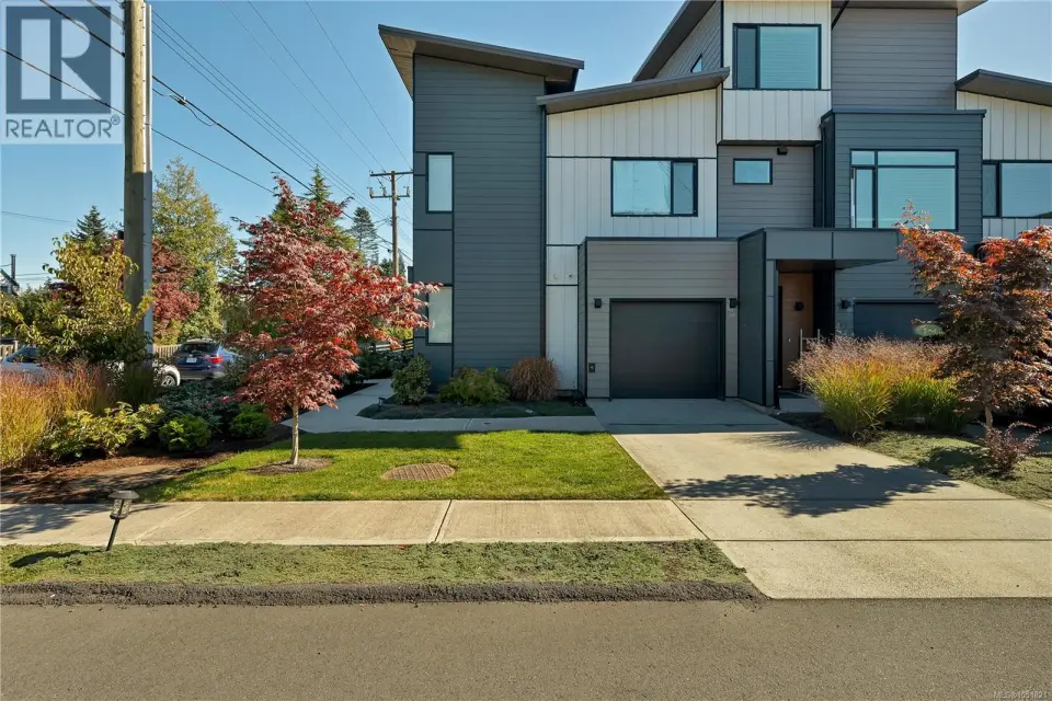 Modern architectural design featuring multi-toned siding, a single-car garage, multiple windows, and a paved driveway